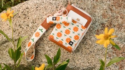 Thread wallet and floral wristlet resting on a granite rock among wildflowers
