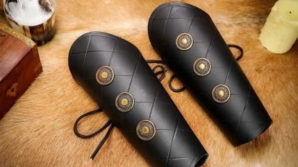 Pair of studded black leather bracers laid out on fur